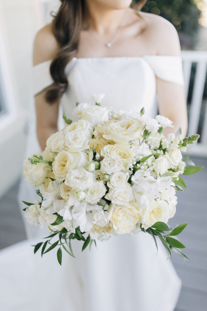 A beautiful bridal portrait of a bride on her wedding day, holding a large neutral bouquet. 