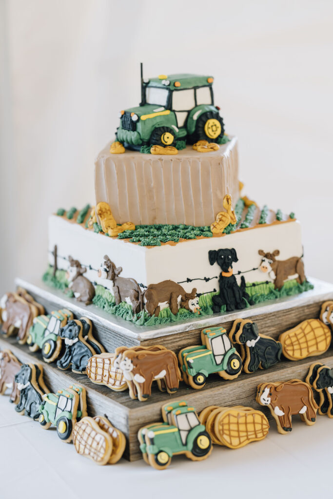 Groom's cake at a wedding reception featuring elements of farming such as a tractor, cows, peanuts, and dogs.